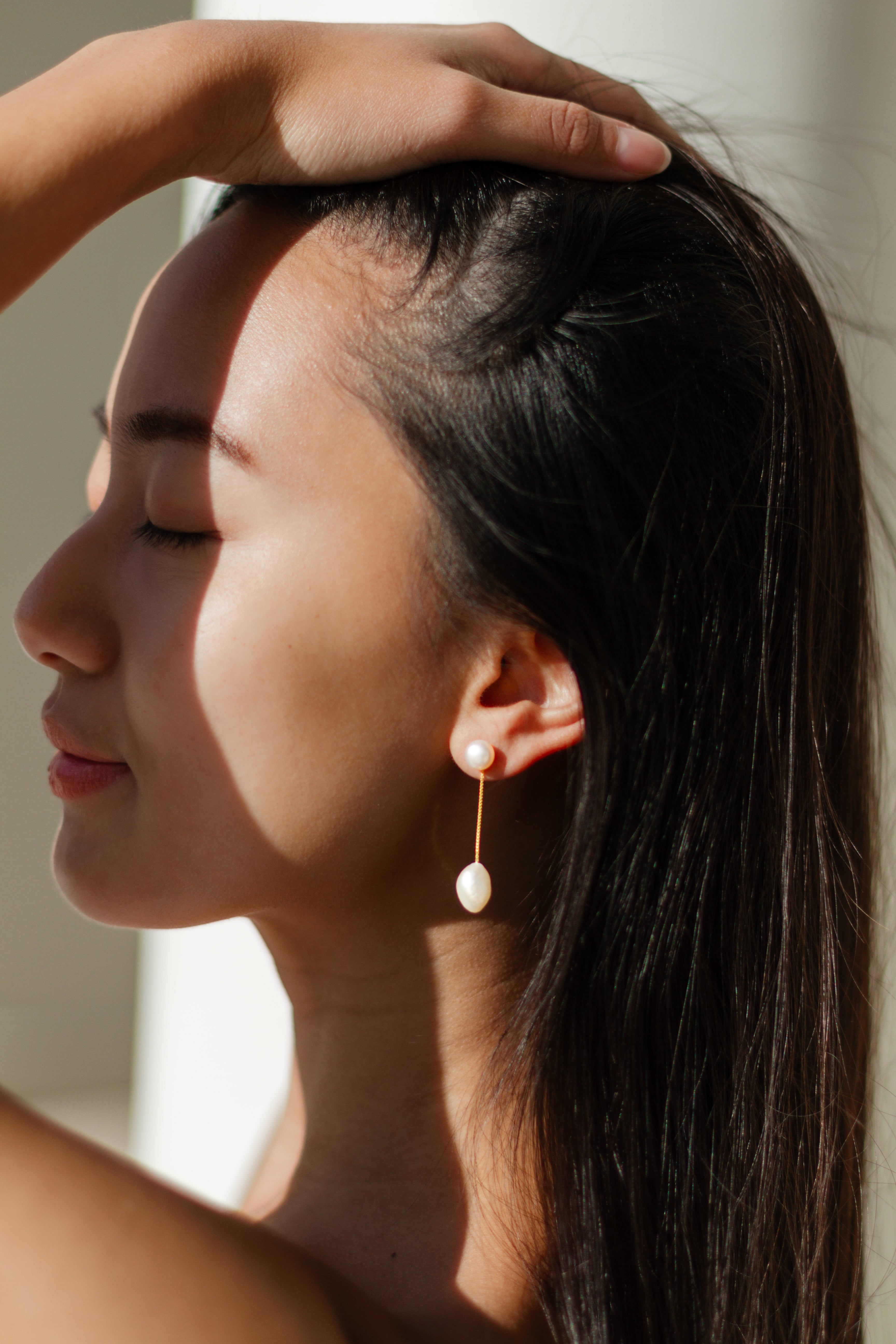 Woman wearing pearl earrings with a soft light background