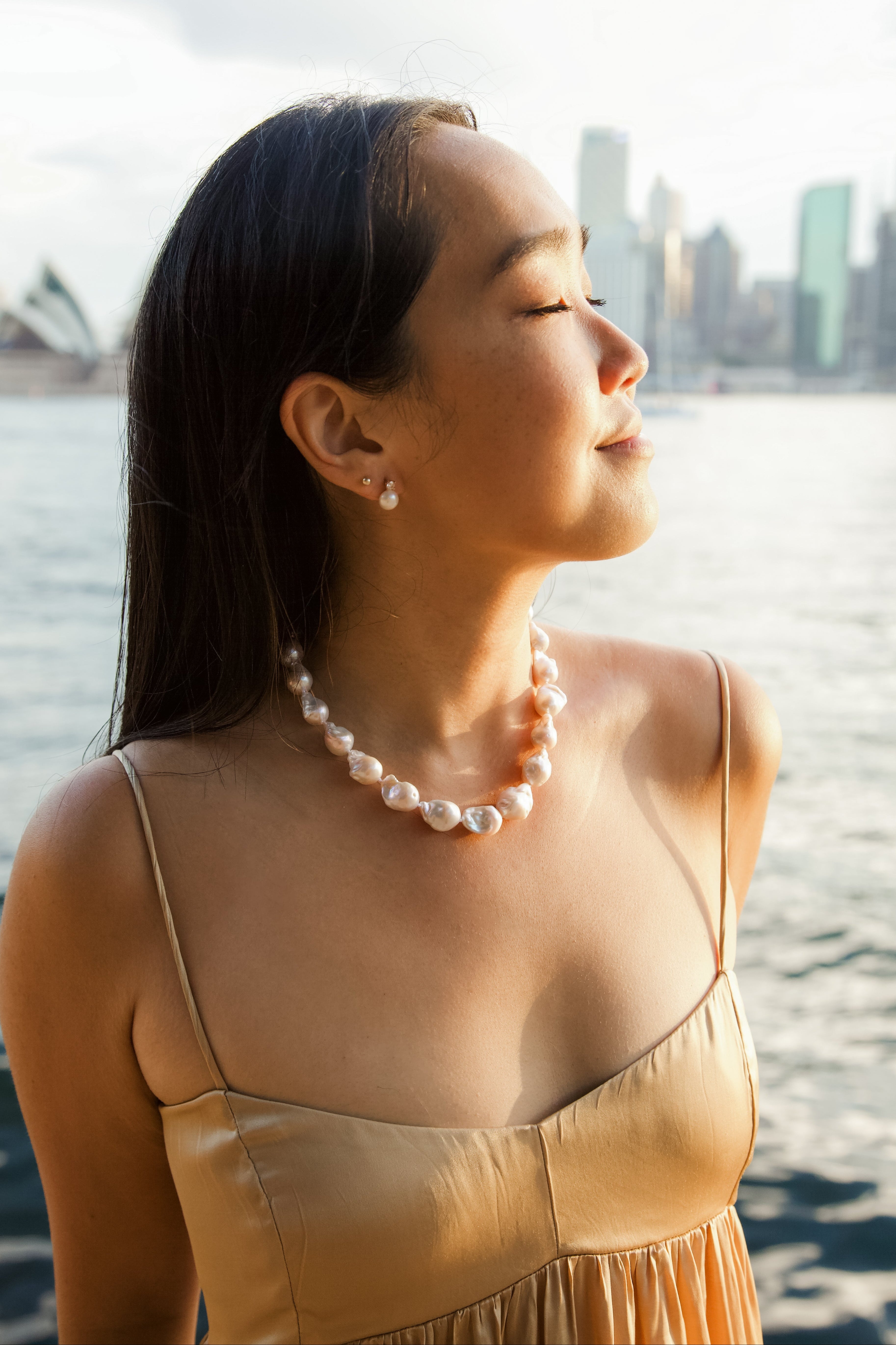 Woman wearing a pearl necklace with a city skyline in the background