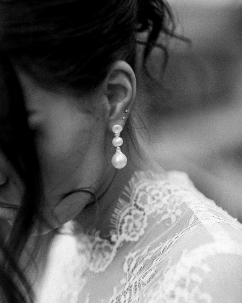 Close-up of a person wearing pearl earrings with a blurred background
